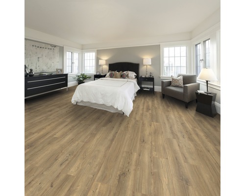 Schlafzimmer mit hellem Laminatboden, Bett, Kommode und Sessel.