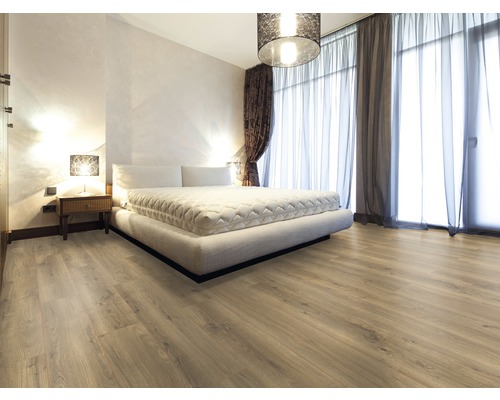 Heller Schlafzimmerraum mit Laminatboden, Bett, Vorhängen und Nachttischlampe.