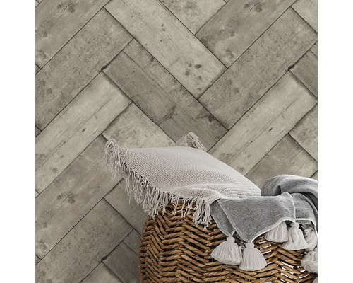 Tapete mit Holzherringbone-Muster, Kissen und Decke in einem Korb