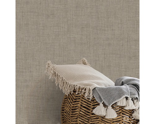 Dekokissen und Decke in einem Korb vor einer strukturierten Wand