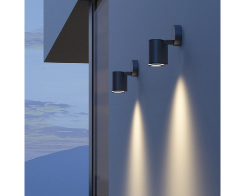 Zwei zylindrische Wandleuchten beleuchten eine Hauswand