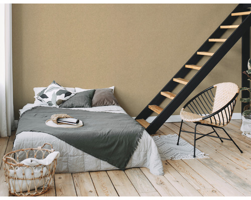 Schlafzimmer mit Bett, Treppe und Sessel vor einer strukturierten Wandtapete