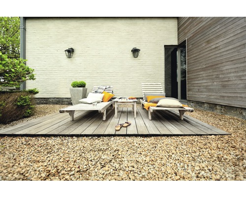 Terrasse mit zwei Liegestühlen, einem kleinen Tisch und dekorativen Kissen auf Kies