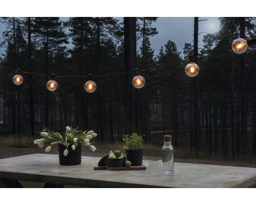 Szene mit Lichterkette und Tischdeko im Garten