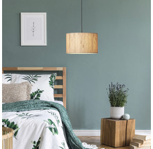 Schlafzimmer mit Holzbett, Nachttisch, Zimmerpflanze, gerahmtem Bild und einer Hängeleuchte aus Holz.