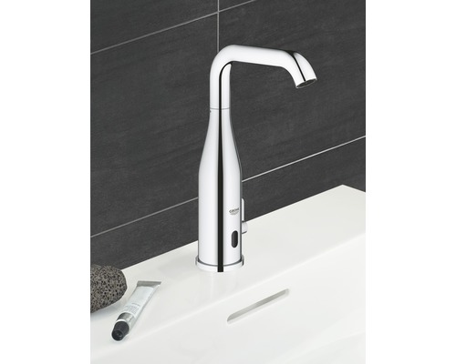 Berührungslose Armatur auf einem Waschbecken mit Pumice Stein und Creme Tube, im Badezimmer.
