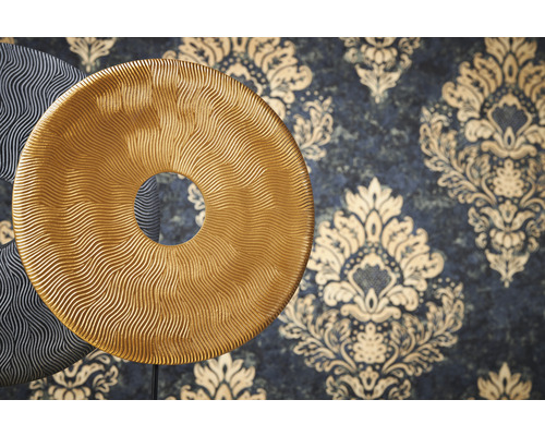 Dekorative Scheiben mit wellenförmiger Struktur vor einer Wand mit floralem Muster.