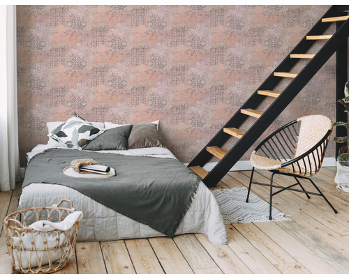 Schlafzimmer mit Bett, Leiter, Rattansessel und gemusterter Tapete für eine gemütliche Atmosphäre