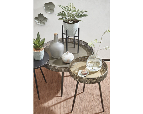 Dekorative Tischgruppe mit Pflanzen, Flaschen und Vasen auf kleinen Beistelltischen.