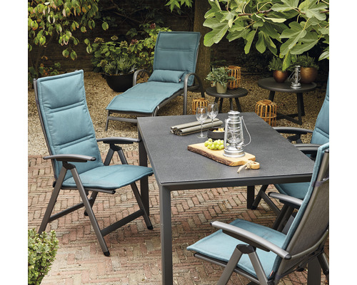 Gartenszene mit Tisch, Stühlen und einer Liege für den Aussenbereich.