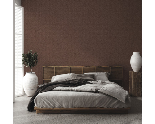 Schlafzimmer mit brauner gemusterter Tapete, Bett, Nachttisch und Zimmerpflanze