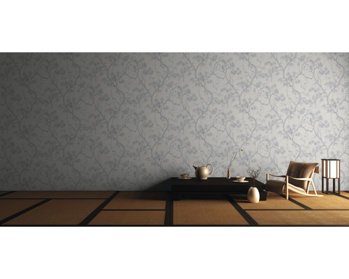 Szene mit Tapete mit Baumdesign, Tisch, Geschirr, Sessel und Lampe.