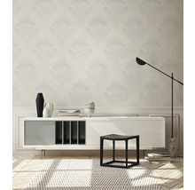 Innenraum mit gemusterter Tapete, Sideboard, Hocker und Teppich
