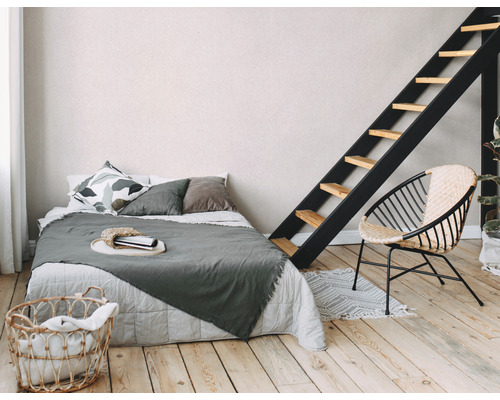 Schlafzimmer mit Bett, Leiter, Korbsessel und Wäschekorb.