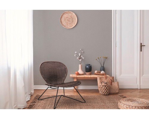 Helles Wohnzimmer mit Rattansessel, Holzbeistelltisch und verschiedenen Dekorationselementen.