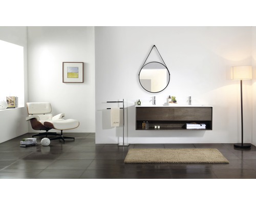 Modernes Badezimmer mit Doppelwaschtisch, rundem Spiegel, Sessel und Stehlampe.