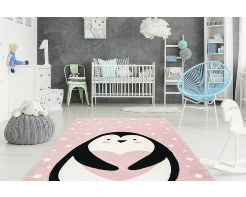 Kinderzimmer mit rosa Teppich mit Pinguinmotiv, Gitterbett und Spielzeug