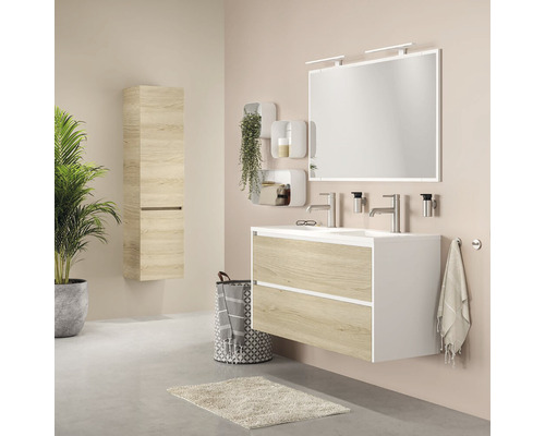 Badezimmer mit Waschtisch, Spiegel, Hängeschrank und Dekorationen für eine helle und freundliche Atmosphäre.