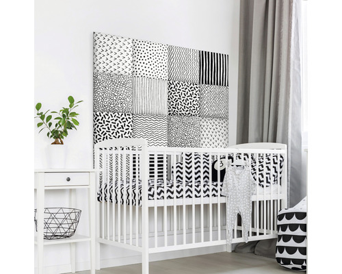 Babyzimmer mit weißem Kinderbett und Wandpaneelen mit verschiedenen Mustern.