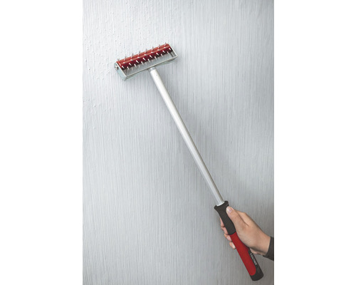 Tapetenandrückroller mit Stiel und Hand auf einer Wand