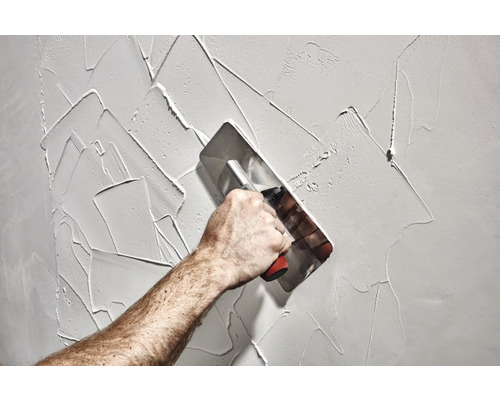 Auftragen von Putz auf eine Wand mit einer Glättkelle