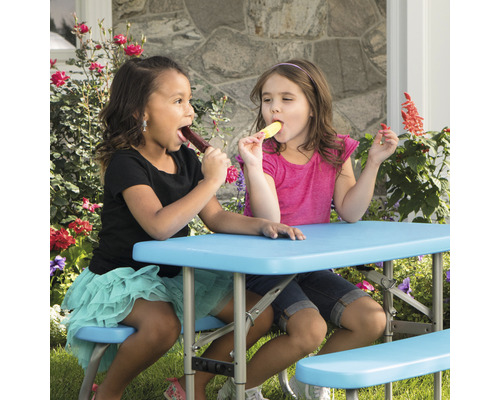 Zwei Kinder sitzen an einem Kindertisch mit Bänken und essen Eis.