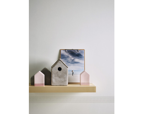 Dekorative Häuser und ein Bild auf einem Holzregal an einer Wand.