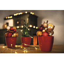 Dekorative Weihnachtsszene mit Kugeln, Orangenscheiben und Lichterketten in roten Übertöpfen