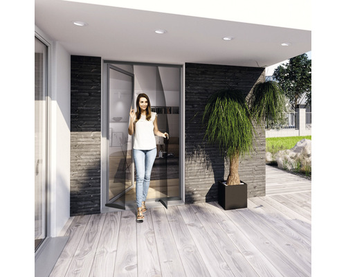 Eine Frau betritt ein modernes Haus mit Schiebetür und Holzterrasse