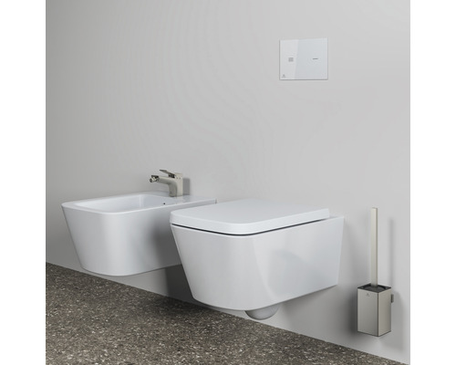 Wandhängendes WC und Bidet mit Betätigungsplatte und WC-Bürste in einem Badezimmer.