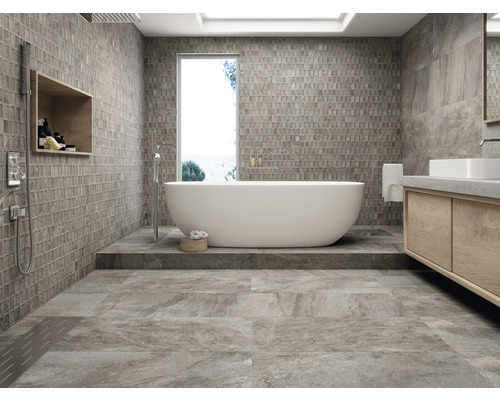Helles Badezimmer mit Badewanne, Waschbecken und gefliesten Wänden und Boden.