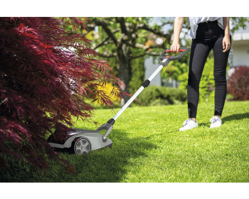 Szene einer Frau, die mit einem Rasentrimmer Gras schneidet