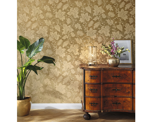 Dekoratives Zimmer mit floraler Tapete, Kommode, Tischleuchte und Zimmerpflanze.