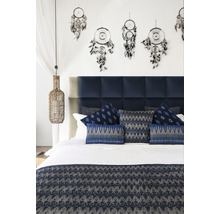Schlafzimmer mit blauem Kopfteil, dekorativen Kissen, Tagesdecke und Traumfängern