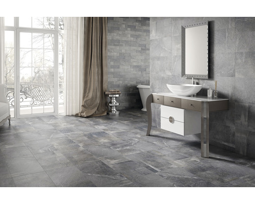 Modernes Badezimmer mit grauen Fliesen an Wand und Boden, Waschtisch, Spiegel und Badewanne.