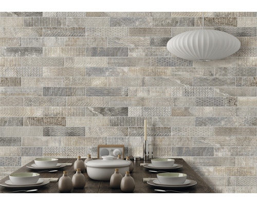 Wandgestaltung mit hellen, länglichen Fliesen in Steinoptik über einem Esstisch.