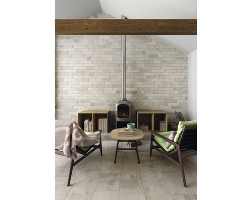 Wohnzimmer mit Kaminofen, Fliesenboden, zwei Sesseln und kleinem Tisch