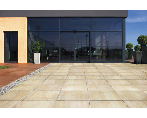 Terrasse mit Terrassenplatten vor einem Gebäude mit Glasfassade.