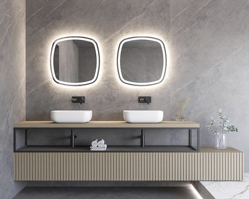 Modernes Badezimmer mit zwei Waschbecken, beleuchteten Spiegeln und Holzverkleidung