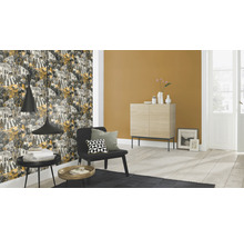 Wohnzimmer mit gemusterter Tapete, Sessel und Beistelltischen.
