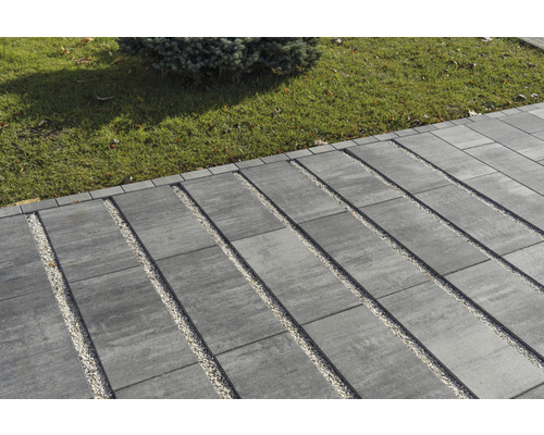Außenbereich mit Pflastersteinen und Kiesstreifen neben einer Rasenfläche