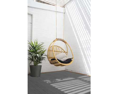 Hängesessel aus Rattan mit Kissen und Pflanze auf Terrasse