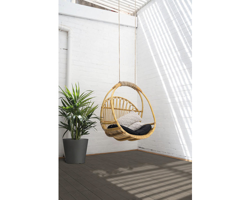 Hängesessel aus Rattan mit Kissen und Pflanze auf einer Terrasse