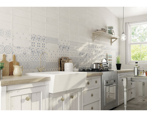 Küchenszene mit weißen Fliesen mit Mustern über der Spüle und dem Herd.