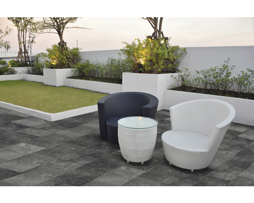 Szene mit zwei Korbsesseln und einem Tisch auf einer Terrasse mit Rasenfläche