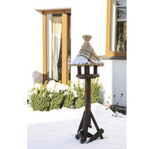 Vogelhaus aus Holz mit Strohdach im winterlichen Garten.
