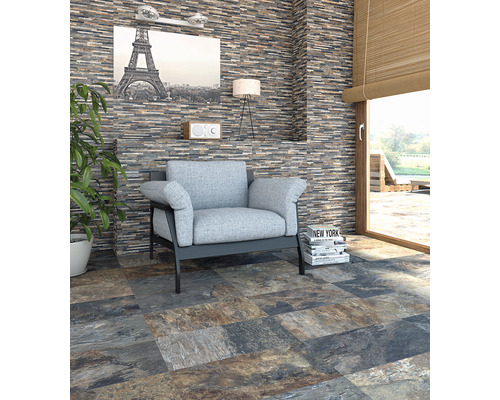 Wohnzimmer mit Wandverkleidung in Steinoptik, Sessel und Bodenfliesen