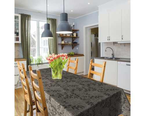 Esstisch mit dunkelgrauer Tischdecke mit Blattmuster in einer hellen Küche.