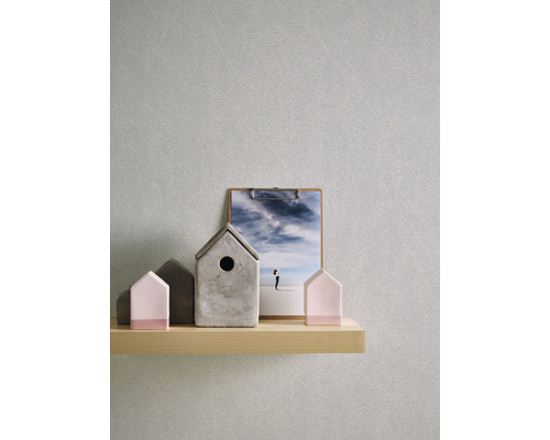 Nahaufnahme einer grauen Tapete mit einer subtilen Struktur, die auf einer hellen Holzablage mit dekorativen Hausobjekten und einer Foto-Klammerbrett-Kombination zu sehen ist. Die Szene strahlt eine ruhige Atmosphäre aus.