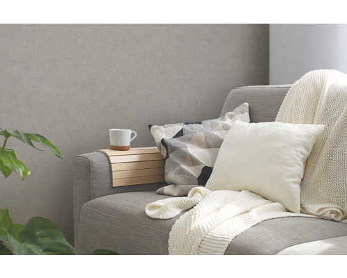 Graues Sofa mit Kissen und einem Getränkehalter aus Holz mit einer Tasse.